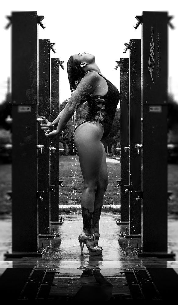 Black and white figure standing among outdoor shower columns