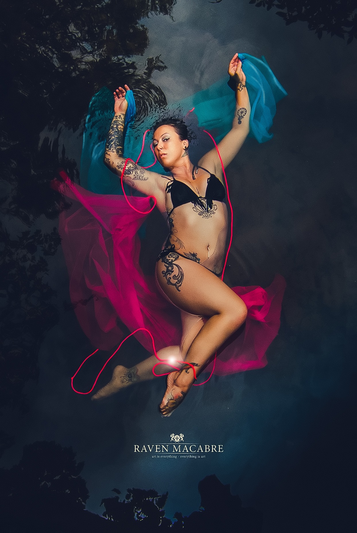 Figure floating in water with bright ribbons and fabric